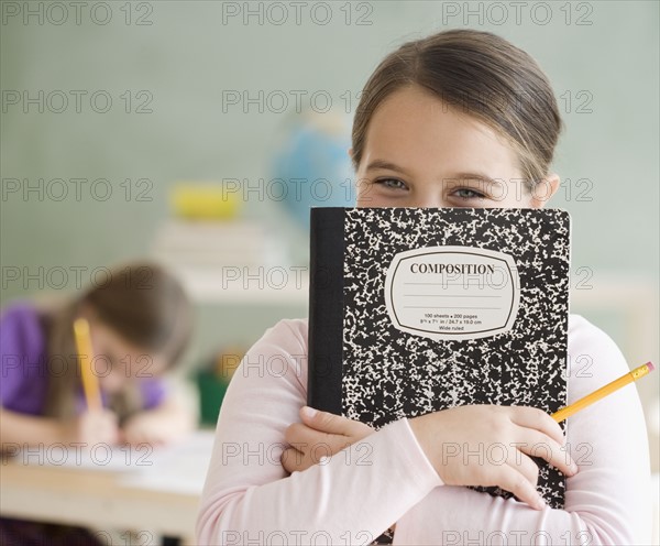 Girl holding notebook in front of face. Date : 2006