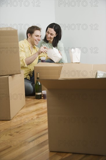 Couple eating take out on boxes in new house. Date : 2006