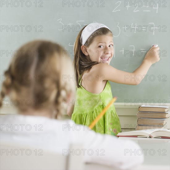 Girl writing on blackboard and smiling. Date : 2006