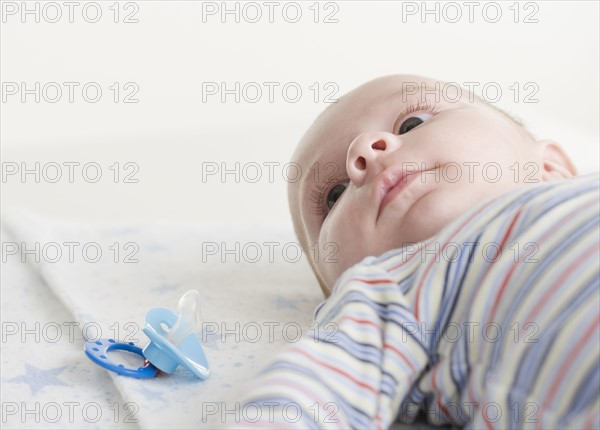 Close up of baby lying down next to pacifier. Date : 2006