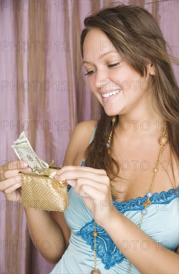 Young woman putting money in change purse. Date : 2006