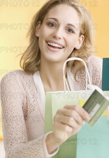 Woman with shopping bags holding credit card   . Date : 2006