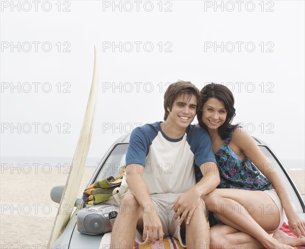 Couple sitting on hood of car at beach. Date : 2006