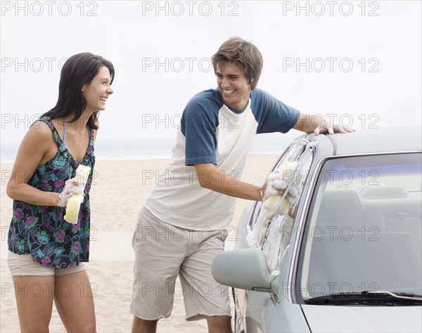 Couple laughing next to car at beach. Date : 2006