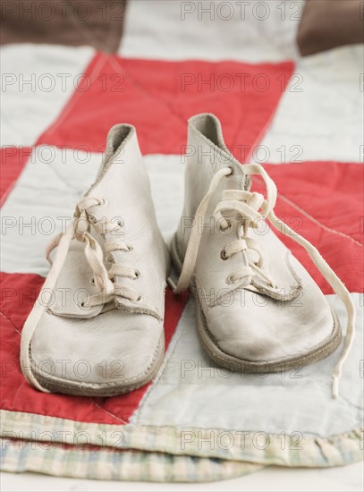 Close up of old fashioned baby shoes on blanket. Date : 2006