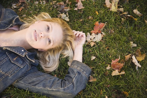 Woman lying in grass on a fall day. Date : 2006