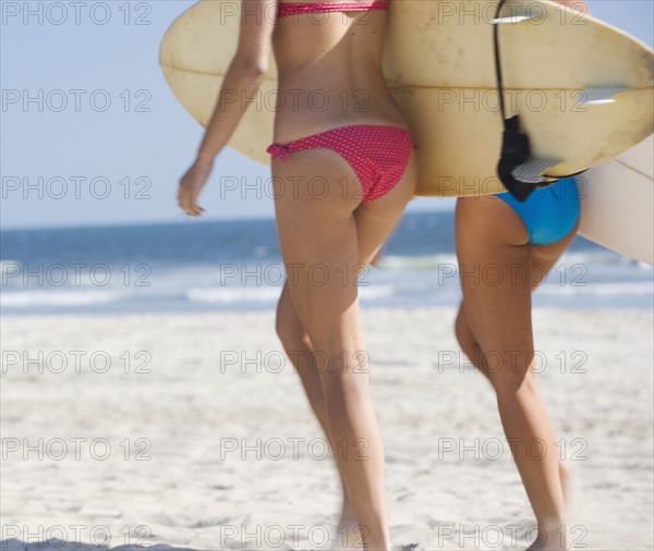 Women in bikinis carrying surfboards. Date : 2006