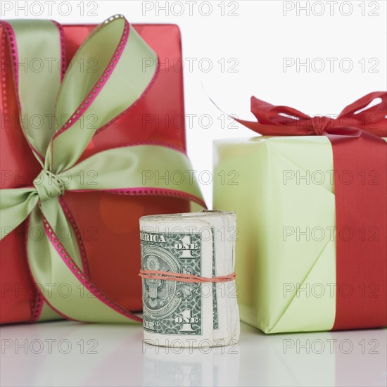Studio shot of roll of dollar bills and gifts. Date : 2006