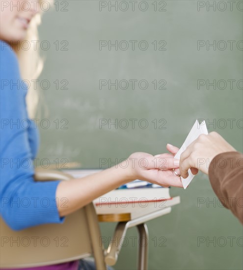 Female student passing a note in class. Date : 2006