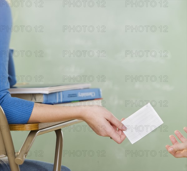 Female student passing a note in class. Date : 2006