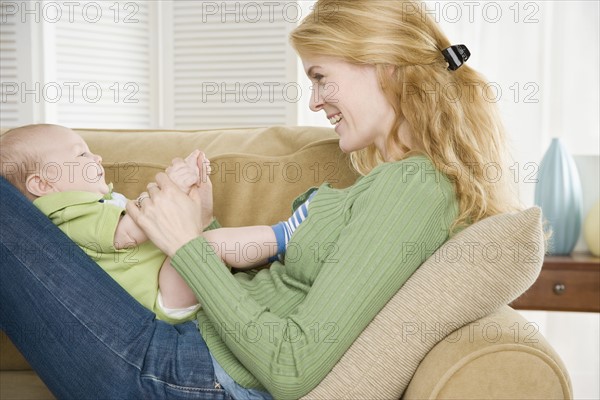 Mother playing with baby on her lap. Date : 2006