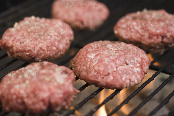 Hamburger patties cooking on grill. Date : 2006