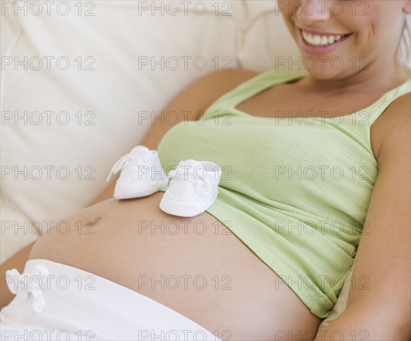 Pregnant woman with baby shoes on belly. Date : 2007