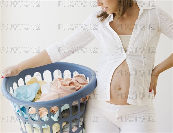 Pregnant woman holding laundry basket. Date : 2007