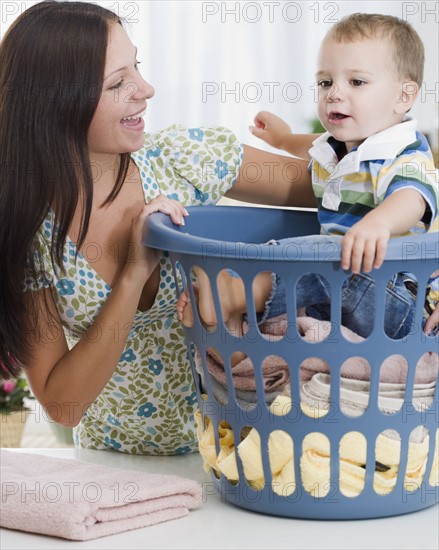 Mother smiling at baby in laundry basket. Date : 2007