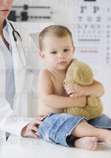 Baby hugging teddy bear at doctor. Date : 2007