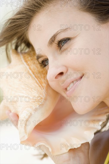 Woman listening to conch shell. Date : 2007