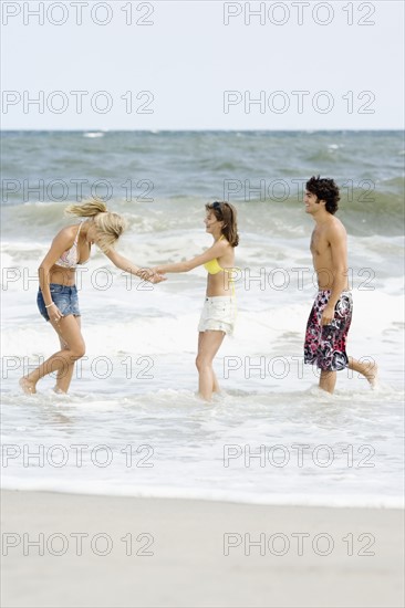 Friends standing in ocean surf. Date : 2007