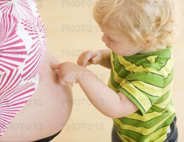 Baby touching mother’s pregnant belly. Date : 2007