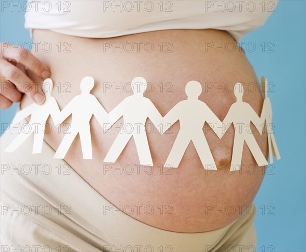Pregnant woman holding paper dolls around belly. Date : 2007