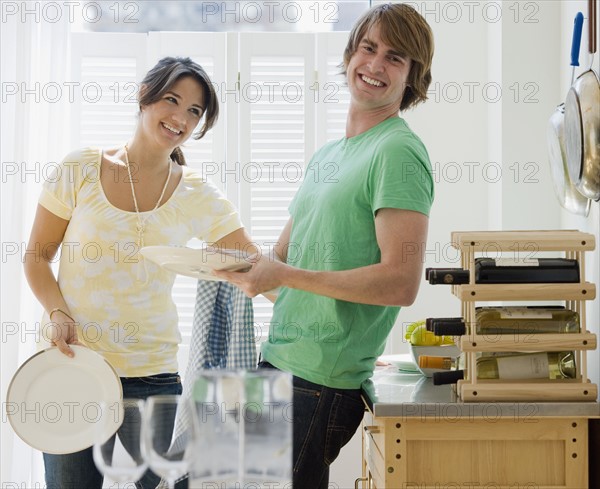 Couple washing dishes in kitchen. Date : 2007