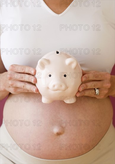 Pregnant woman holding piggy bank. Date : 2007