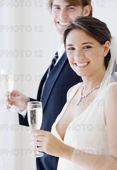 Bride and groom holding champagne glasses. Date : 2007
