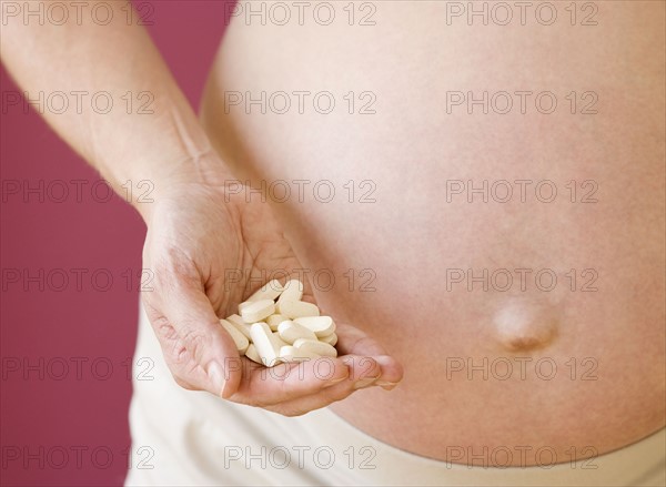 Pregnant woman holding handful of vitamins. Date : 2007