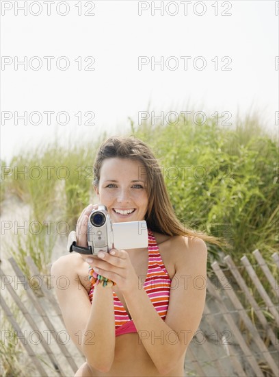 Woman holding video camera at beach. Date : 2007