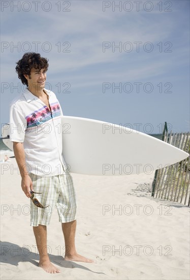 Man holding surfboard at beach. Date : 2007