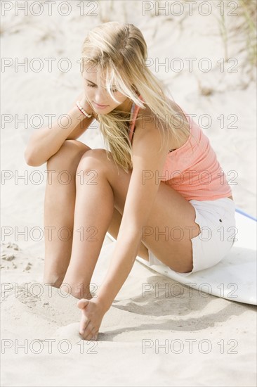 Woman sitting on surfboard at beach. Date : 2007