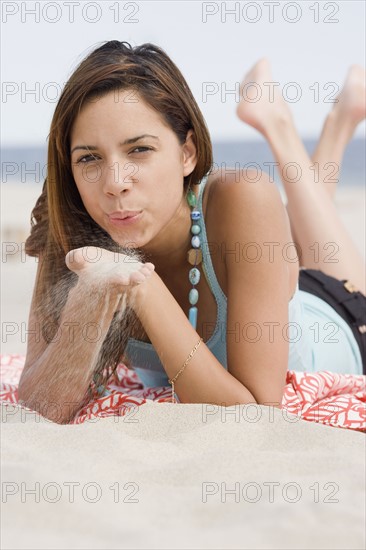 Woman blowing on sand in hands. Date : 2007