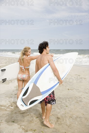 Couple holding surfboards at beach. Date : 2007