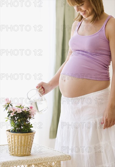 Pregnant woman watering plant. Date : 2007