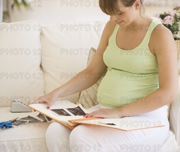 Pregnant woman putting ultrasound in photo album. Date : 2007