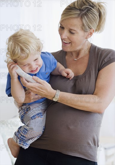 Pregnant mother holding child on telephone. Date : 2007