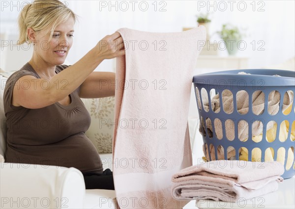 Pregnant woman folding laundry. Date : 2007