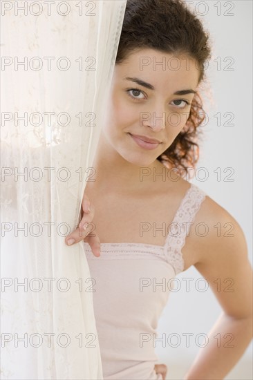 Woman looking out from behind curtain. Date : 2007