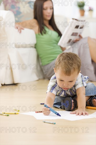 Mother reading while baby colors. Date : 2007