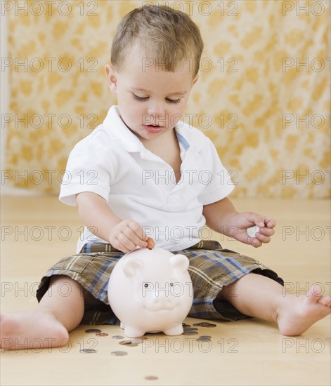 Baby putting coins in piggy bank. Date : 2007