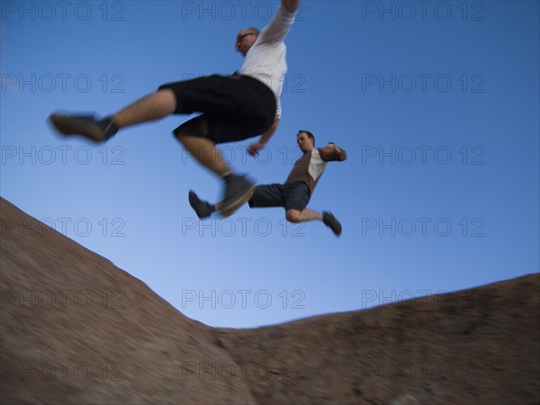 Men jumping over rock formations. Date : 2007