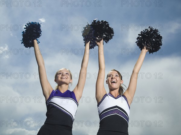 Two cheerleaders holding pom poms over head. Date : 2007