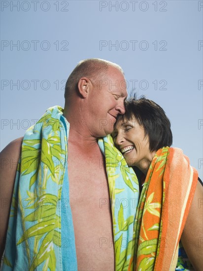 Couple with beach towels hugging. Date : 2007