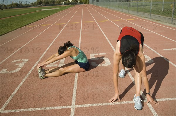 Female runners stretching on track, Utah, United States. Date : 2007