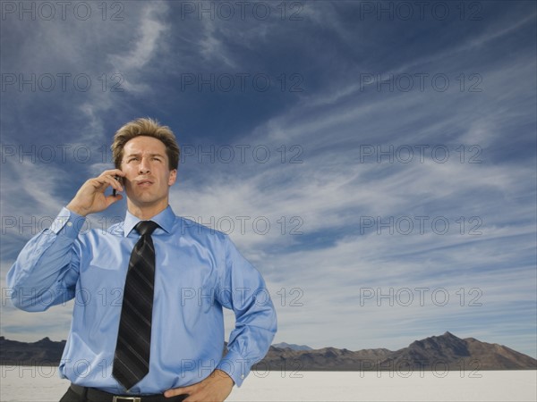 Businessman talking on cell phone, Salt Flats, Utah, United States. Date : 2007