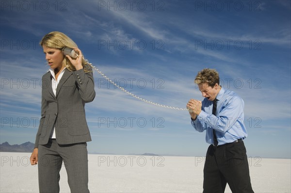 Businesspeople talking with can and string phone, Salt Flats, Utah, United States. Date : 2007
