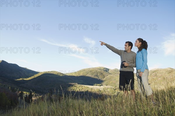 Couple holding binoculars and pointing, Utah, United States. Date : 2007