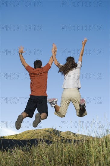 Rear view of couple jumping, Utah, United States. Date : 2007