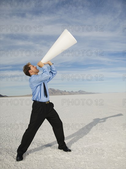 Businessman yelling into megaphone, Salt Flats, Utah, United States. Date : 2007