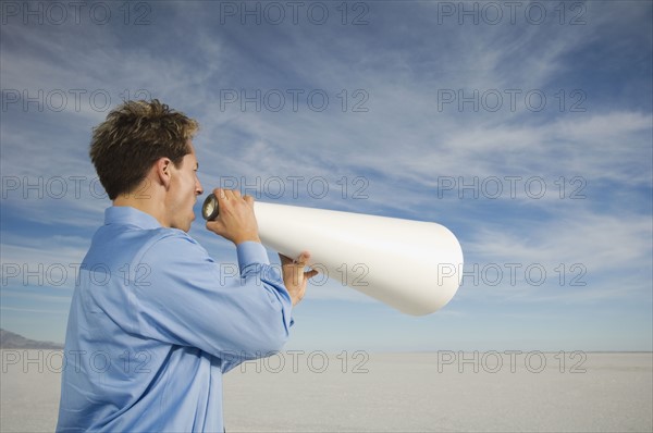 Businessman yelling into megaphone, Salt Flats, Utah, United States. Date : 2007